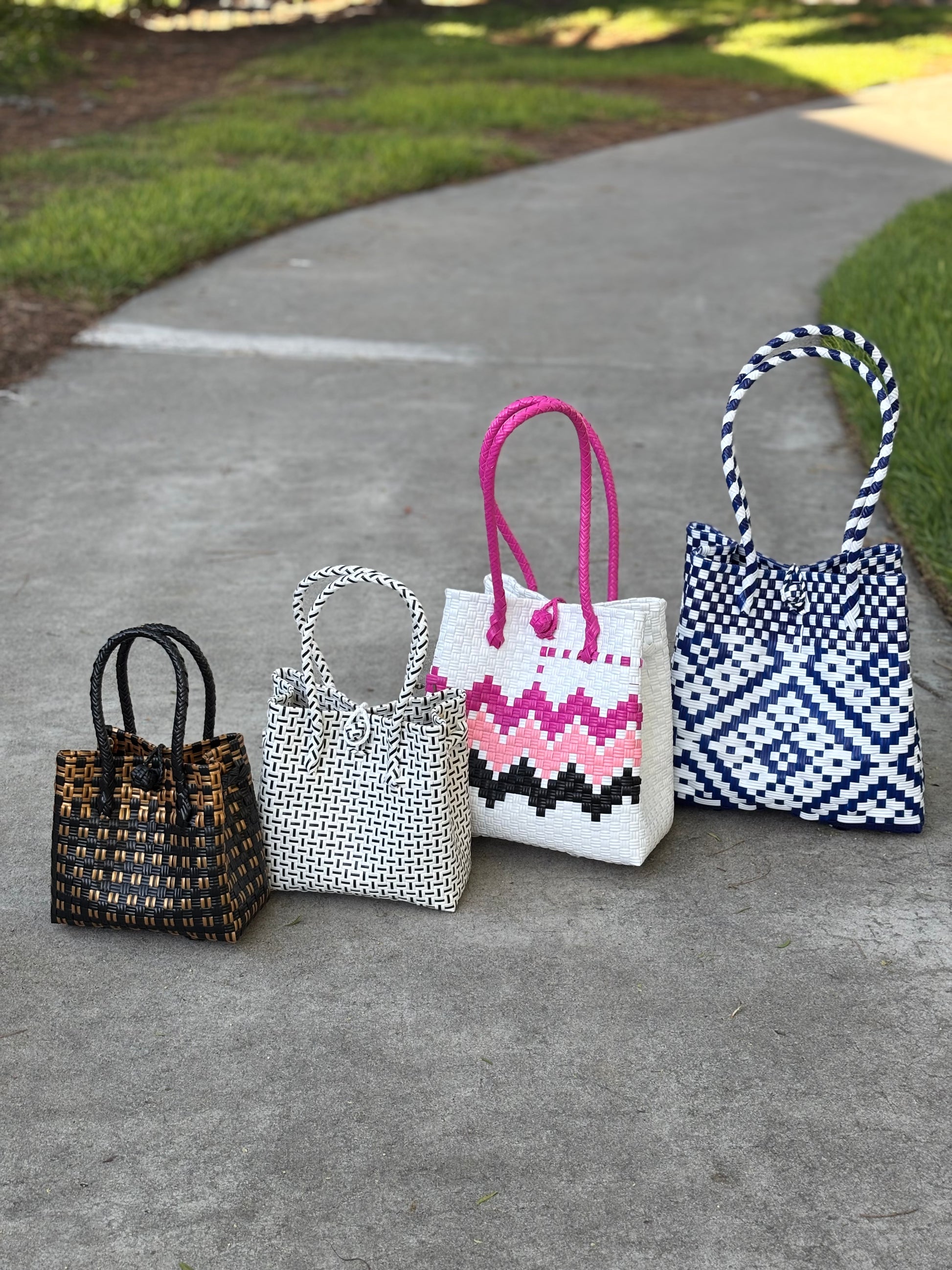 Five handbags of different styles and colors on a concrete surface
