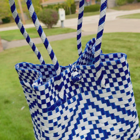 Sustainable recycled plastic tote bag in blue and white pattern on grass.